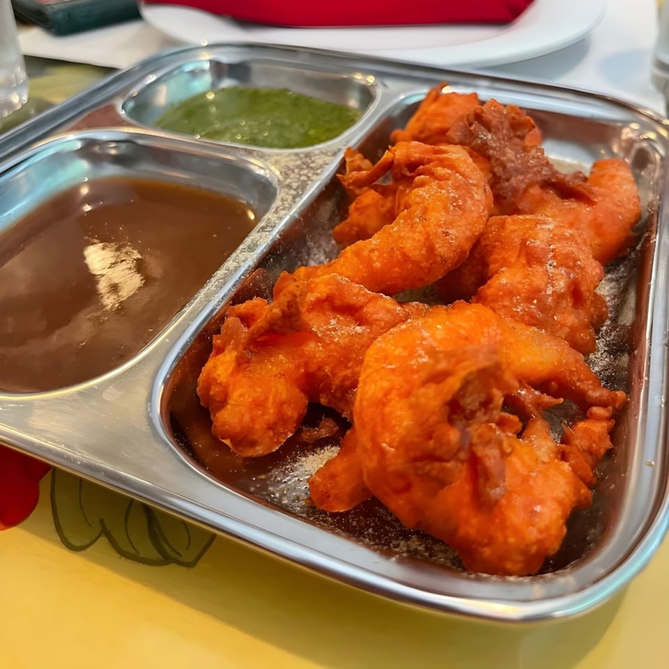 Himalayan Kitchen's Indian pakora, a fried snack, served with two dipping sauces in a metal tray.