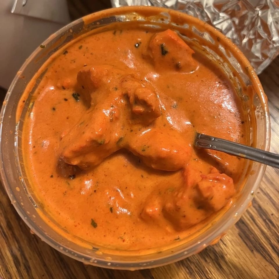 Himalayan Kitchen's chicken tikka masala in a plastic container with a spoon.